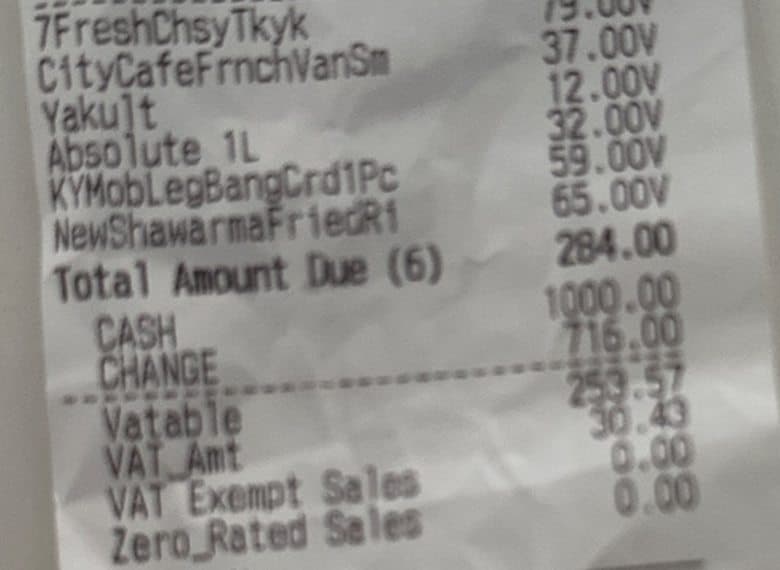 A crumpled, blurry 7-Eleven invoice. The VATable amount is hard to read.